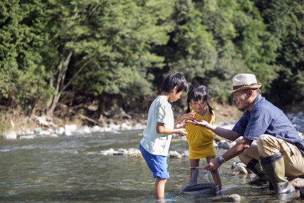ลุงกำลังโชว์เปลือกหอยให้เด็กผู้หญิงและผู้ชายดูที่ริมแม่น้ำ