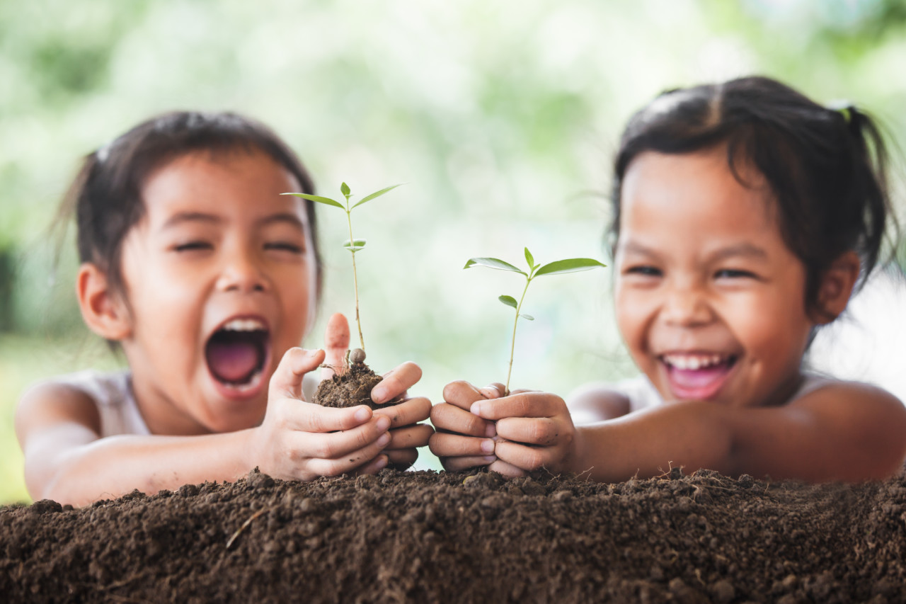 เด็กสองคนยิ้มให้กับพืชที่กำลังเติบโต