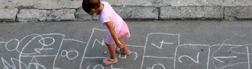 A girl playing hopscotch in the street.