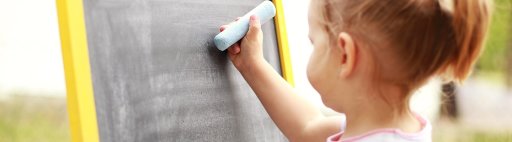Little girl about to draw with blue chalk on a chalkboard.