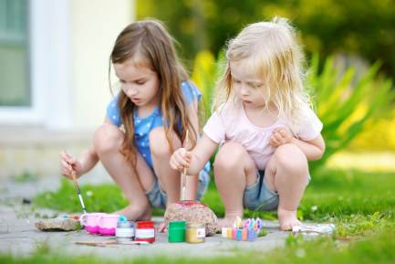 เด็กผู้หญิงสองคนพี่และน้องกำลังทาสีอยู่ในสวนหลังบ้าน